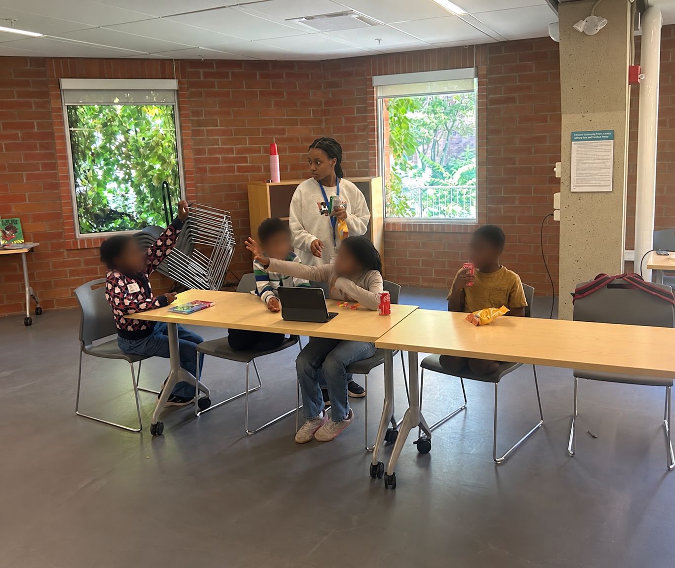 A volunteer supports young learners at a table during a STEM session.
